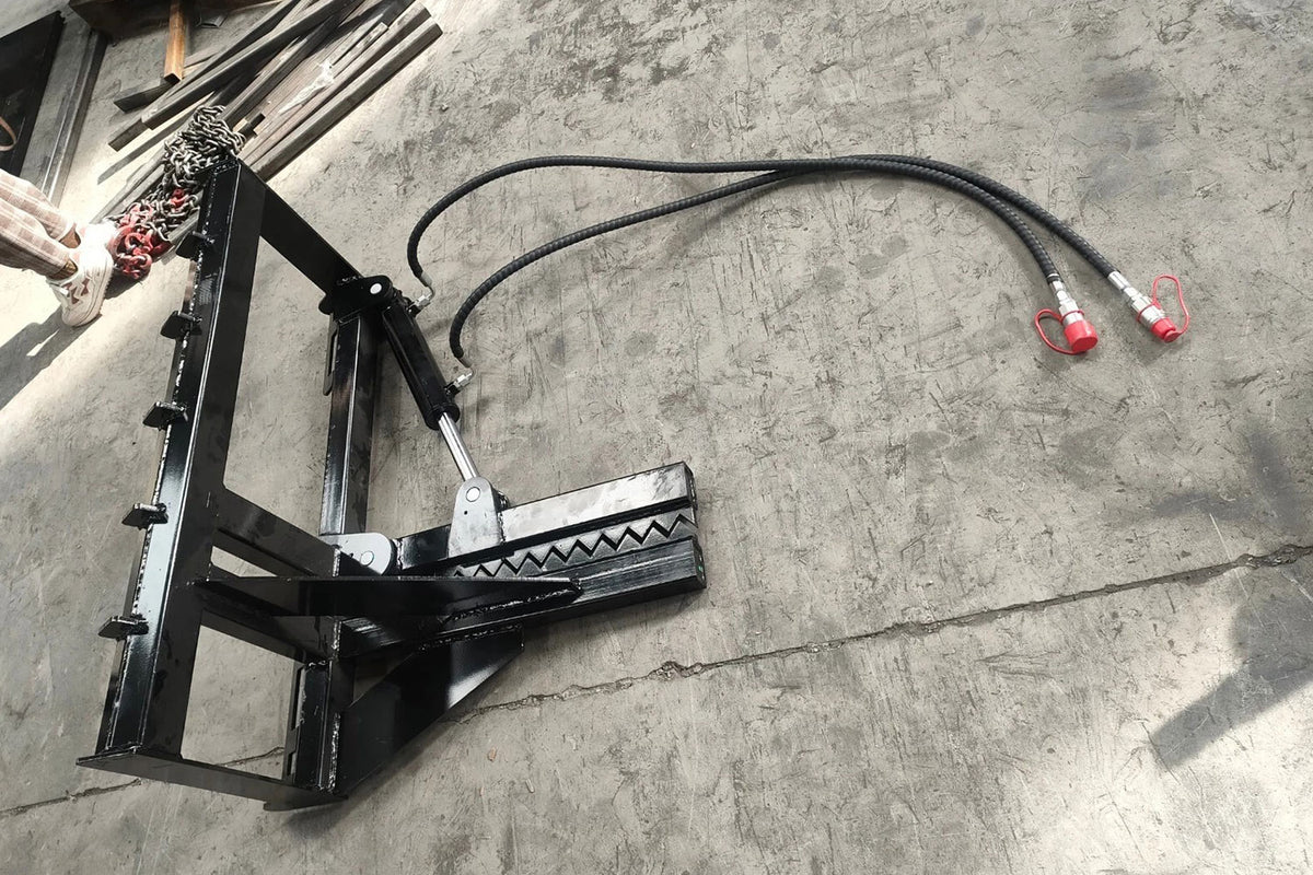 Black skid steer tree puller attachment with hydraulic hoses and red couplers, post puller