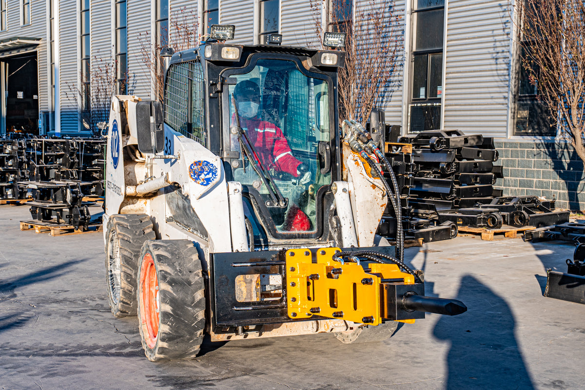 Skid steer loader with yellow hydraulic hammer breaker attachment and chisel rod