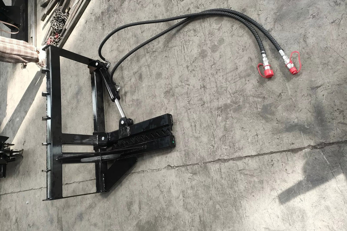 Black skid steer tree puller attachment with hydraulic hoses and red couplers