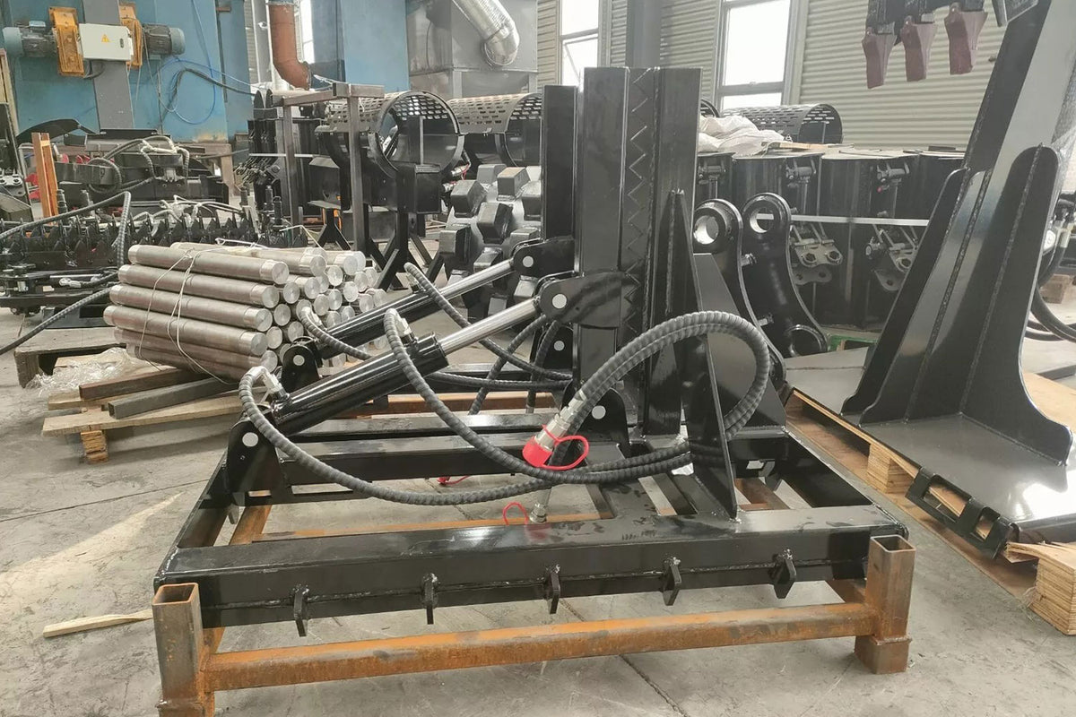 Black skid steer tree puller attachment with hydraulic cylinders in workshop