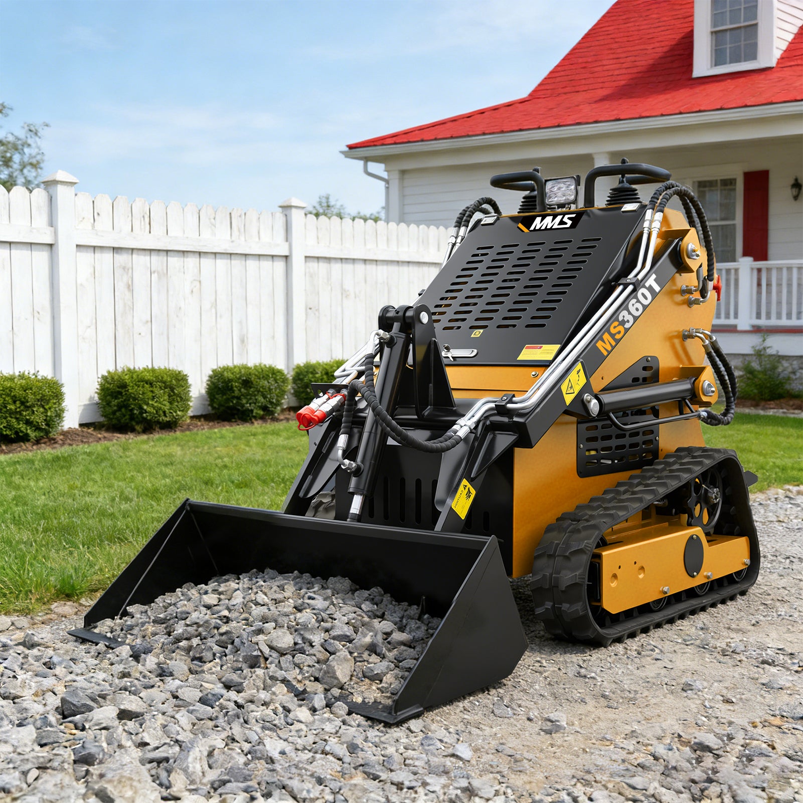 Small tracked loader on a gravel driveway with a house in the background