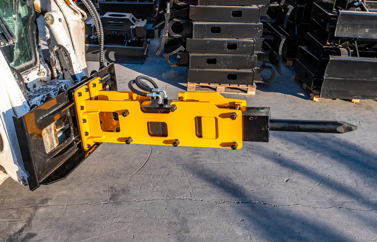 Yellow skid steer hydraulic breaker and pile driver attachment with black steel pile