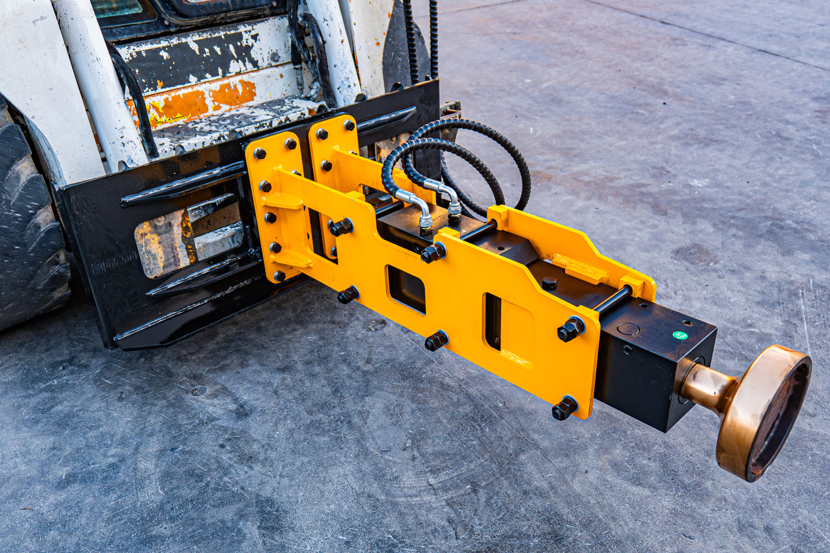 Yellow skid steer hydraulic pile driver attachment with black housing and steel driving head